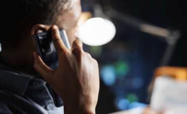 African american guy talks on phone call working from home, discusses online records with another employee. Young person contacts legal expert to chat about business accounting.